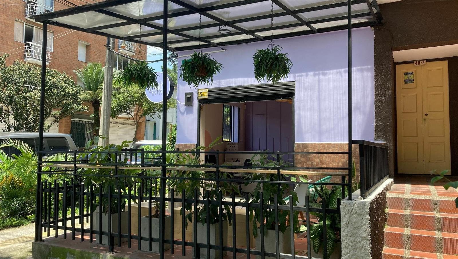Entrada de Lilah: casa lila con reja negra, plantas y helechos